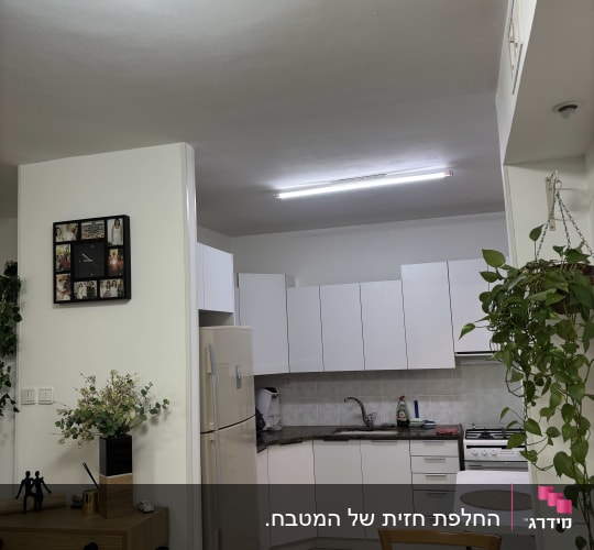 מטבח עם ארונות לבנים ושולחן אוכל